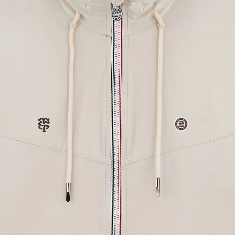 Détail de la veste écrue zippée et des logos de la collaboration
