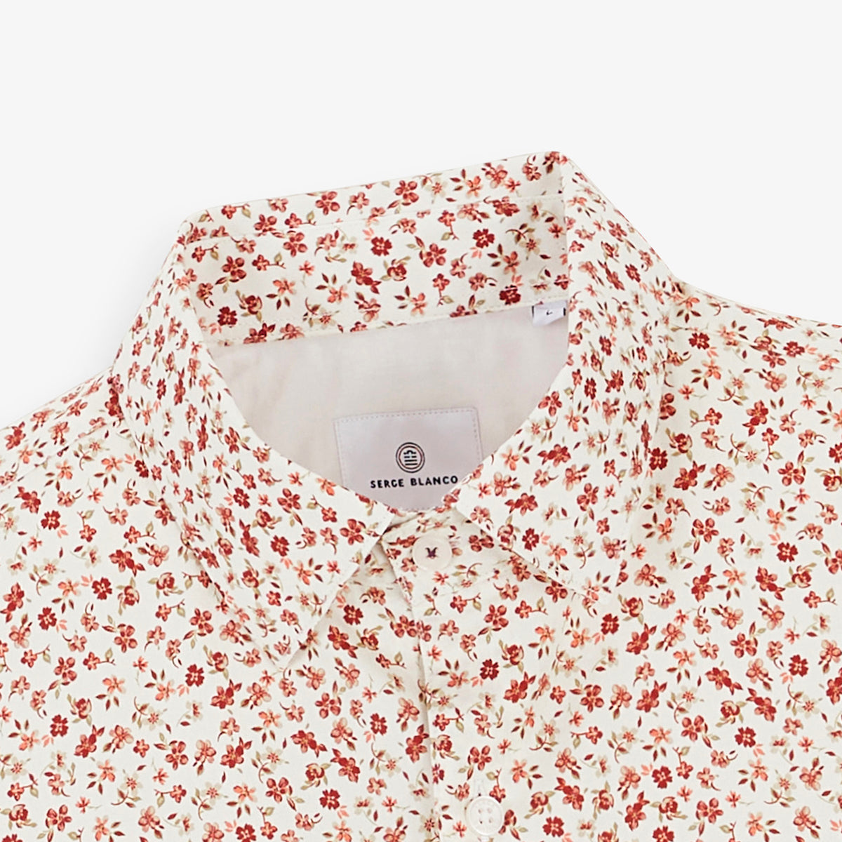 Détail du col et du motif de petites fleurs rouges de la chemise en coton.