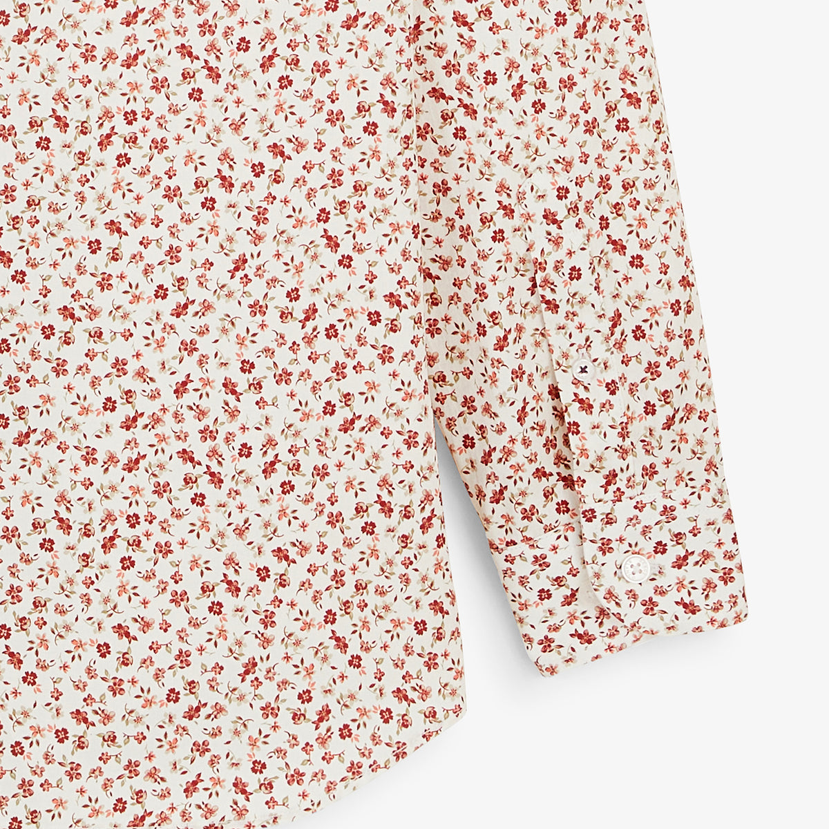 Détail du poignet boutonné de la chemise à petites fleurs rouges.