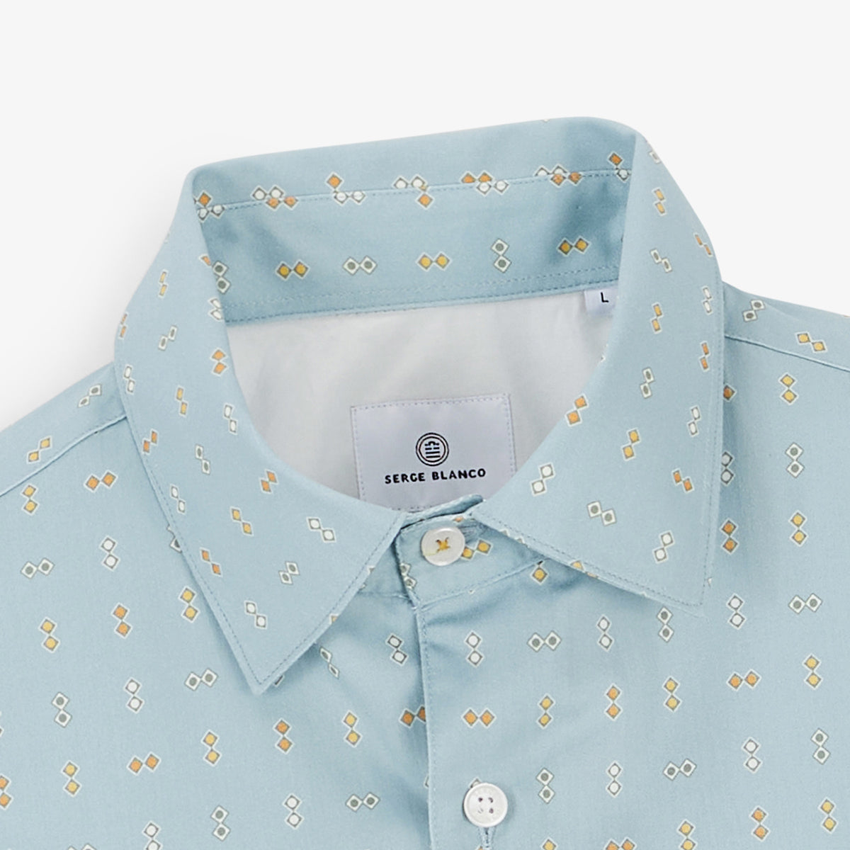 Gros plan sur le col et le motif losanges de la chemise bleu clair.