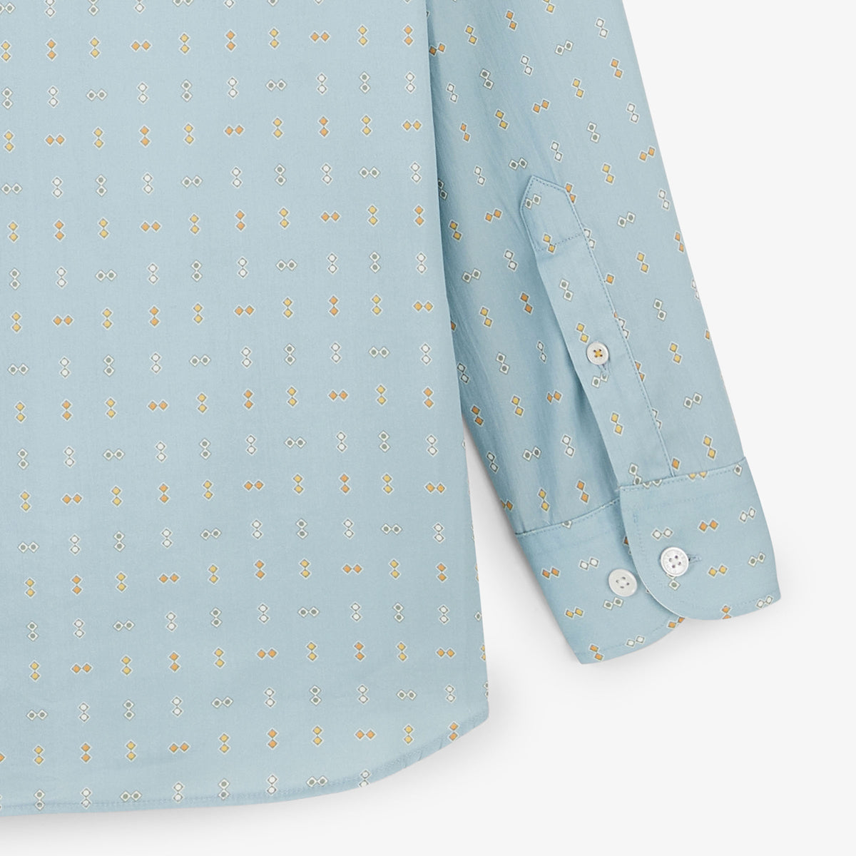Gros plan sur le bas et le poignet boutonné de la chemise bleu clair à motif losanges.