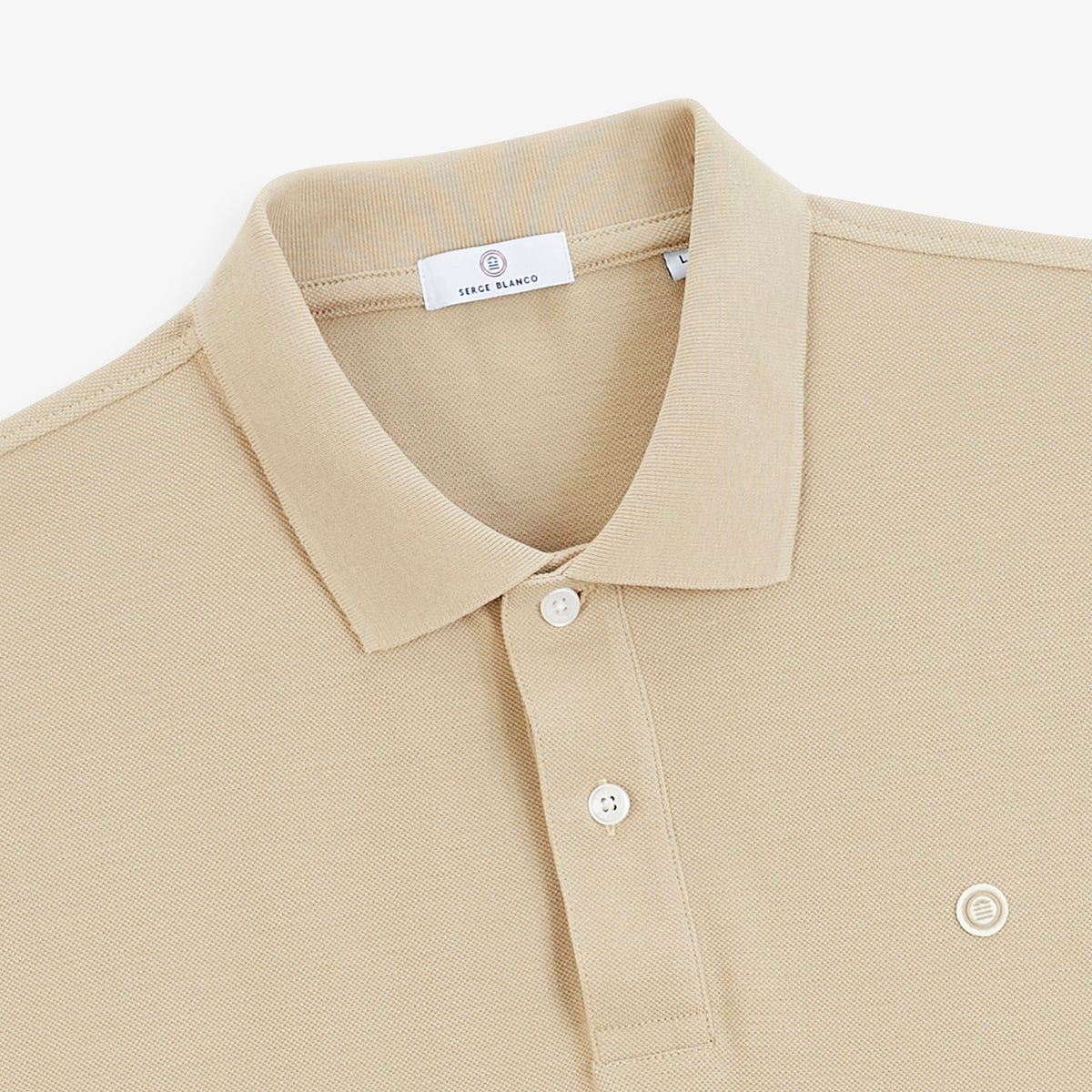 Détail du col, des deux boutons blancs et du logo poitrine du polo piqué Lucas beige travertin SERGE BLANCO.