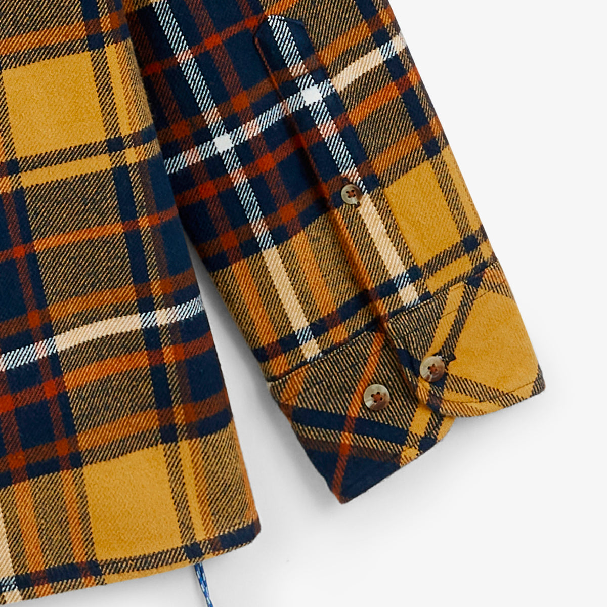 Primo piano sulla parte inferiore e sul polsino abbottonato della sovracamicia a quadri tartan giallo senape SBPLAY.