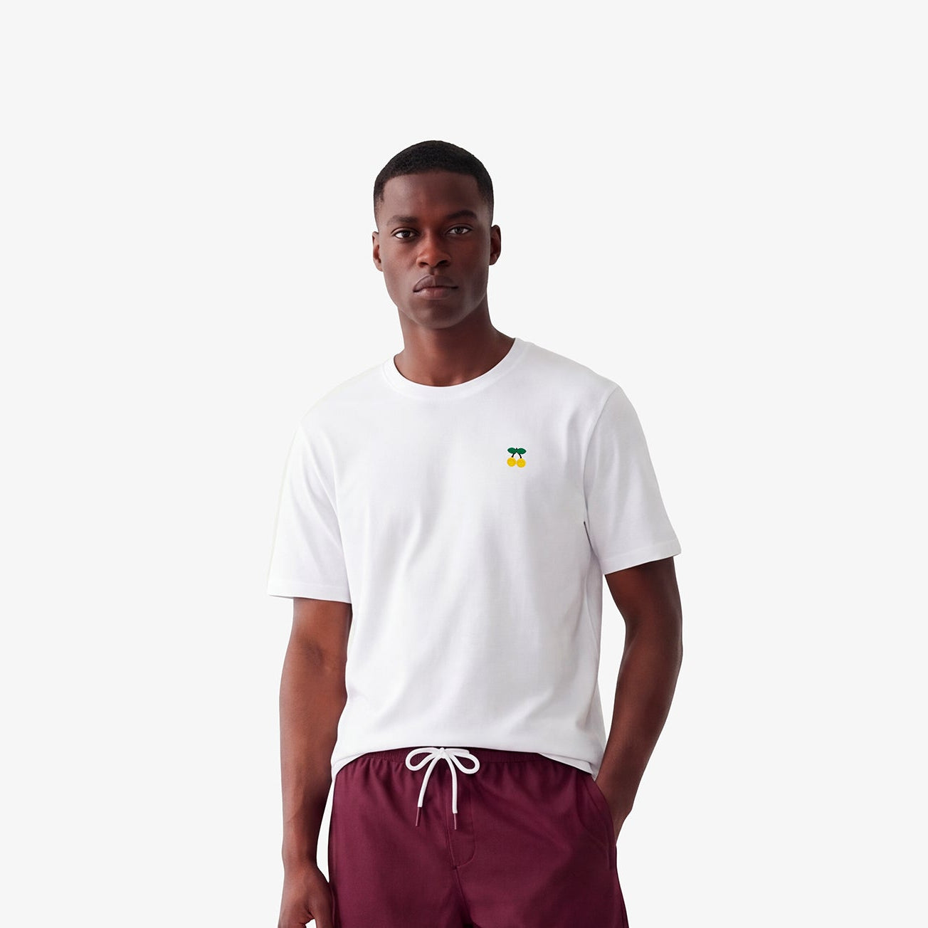 Camiseta de cuello redondo de algodón blanco con bordado de cerezas amarillas en el pecho.